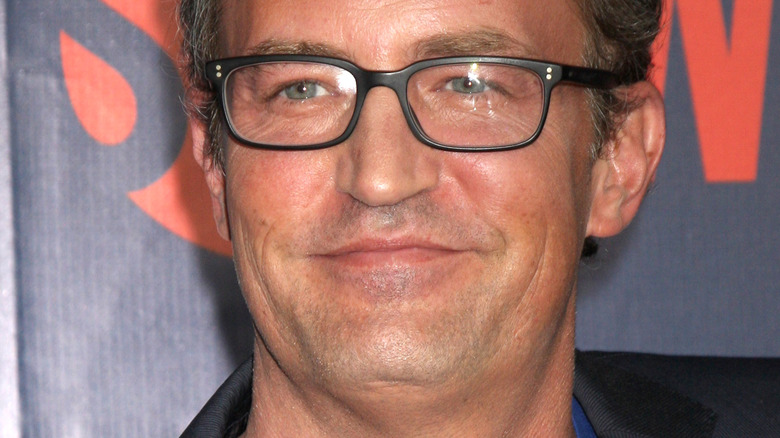 Matthew Perry smiling with glasses on