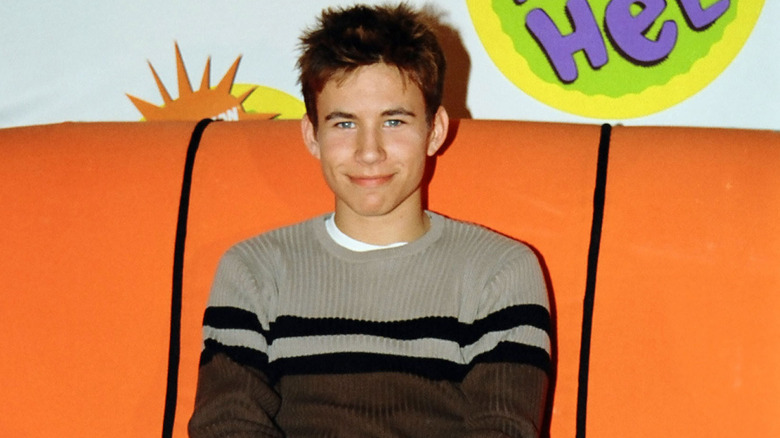 Jonathan Taylor Thomas posing at an event in a stripy sweater in 1998