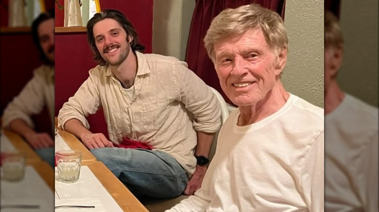 Conor Schlosser and Robert Redford posing together at a restaurant.