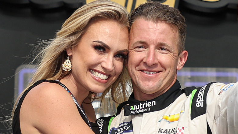 A.J. Allmendinger and Tara Allmendinger smiling and holding one another after a race