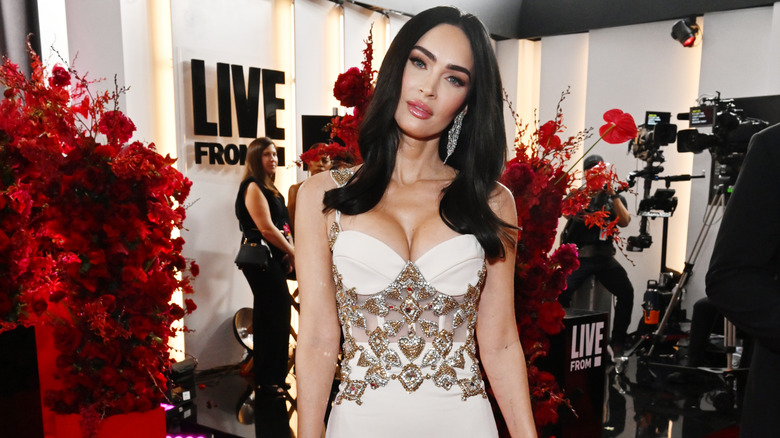 Megan Fox center parted long dark hair diamond earrings