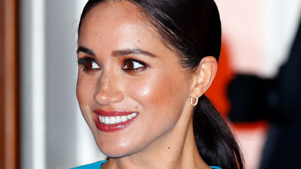 Meghan Markle smiles in red lip gloss and ponytail