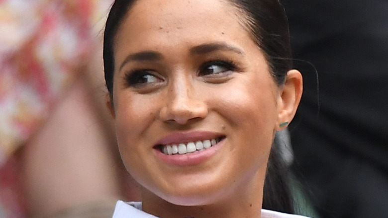 Meghan Markle grinning and looking to her side