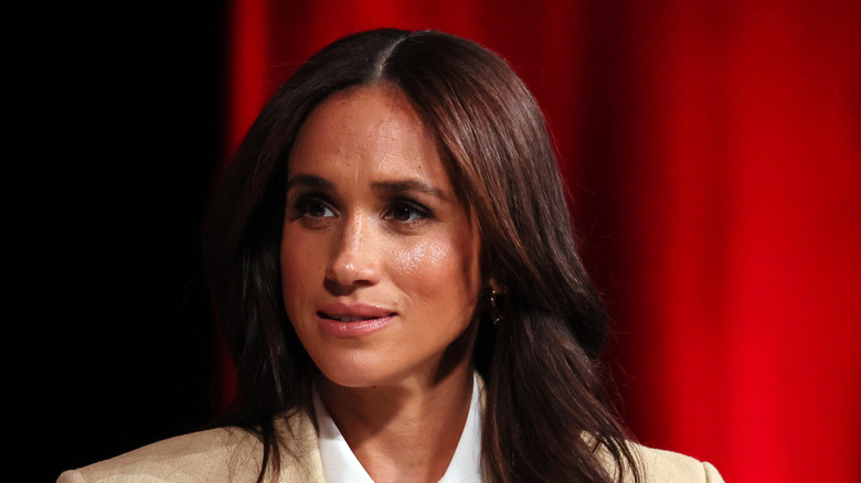 Meghan Markle staring sideways in a tan suit.