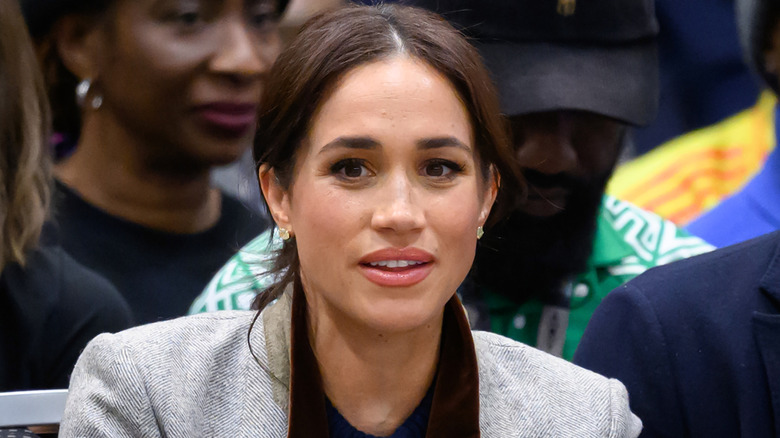 Meghan Markle sitting down while watching a basketball match.