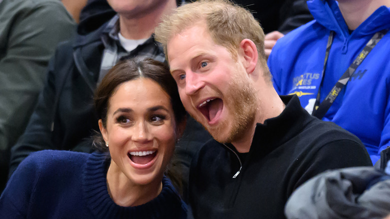 Meghan Markle and Prince Harry smiling at an outdoor event