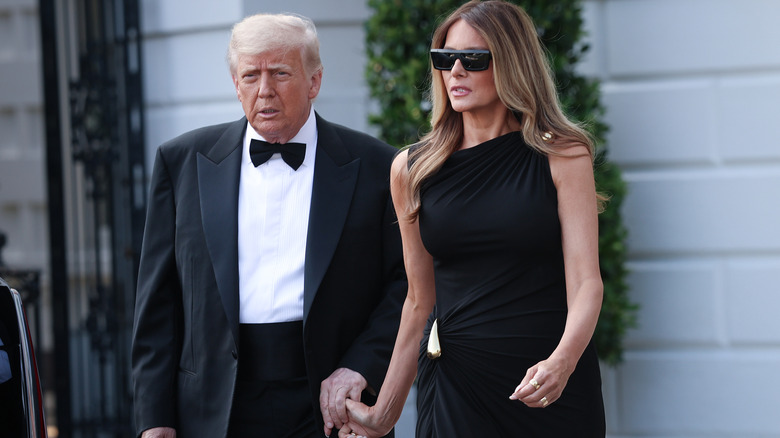 Melania and Donald Trump holding hands on the red carpet.