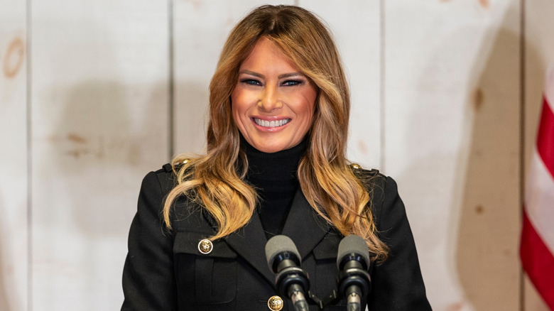 Melania Trump smiling at a podium with lighter hair in 2020