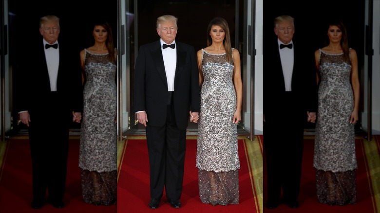 Donald and Melania Trump holding hands while standing