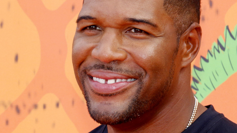 Michael Strahan smiles in a black shirt