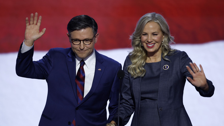 Mike Johnson and wife Kelly waving while wearing navy at an event