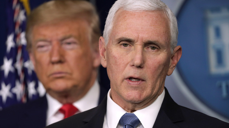Donald Trump stands behind Mike Pence as he speaks into a mic