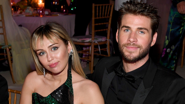 Miley Cyrus seated at table with Liam Hemsworth