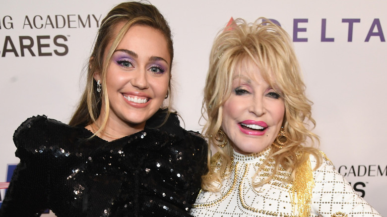 Up-close photo of Miley Cyrus and Dolly Parton posing and smiling together.