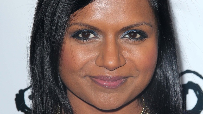 Mindy Kaling smiles wearing blue eyeshadow