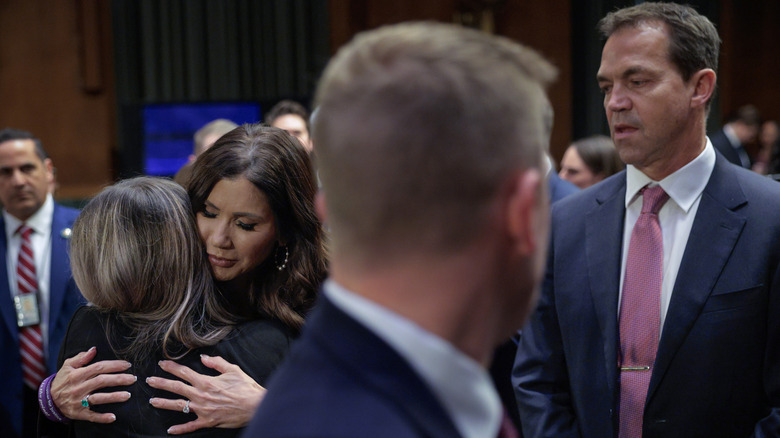 Bryon Noem looks on as Kristi Noem hugs someone following her congressional hearing