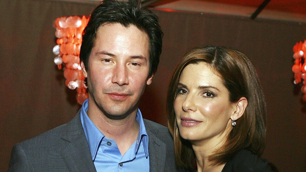Keanu Reeves standing next to Sandra Bullock