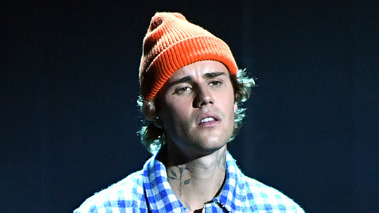 Justin Bieber performing onstage in orange beanie