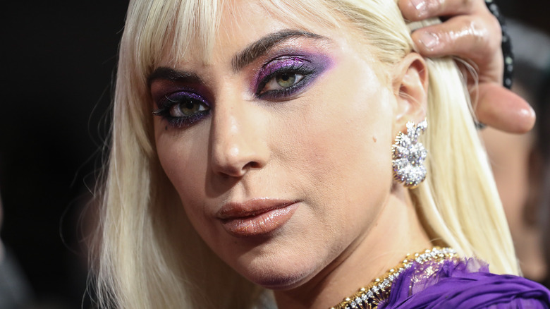 Lady Gaga smiling with a hand on her head
