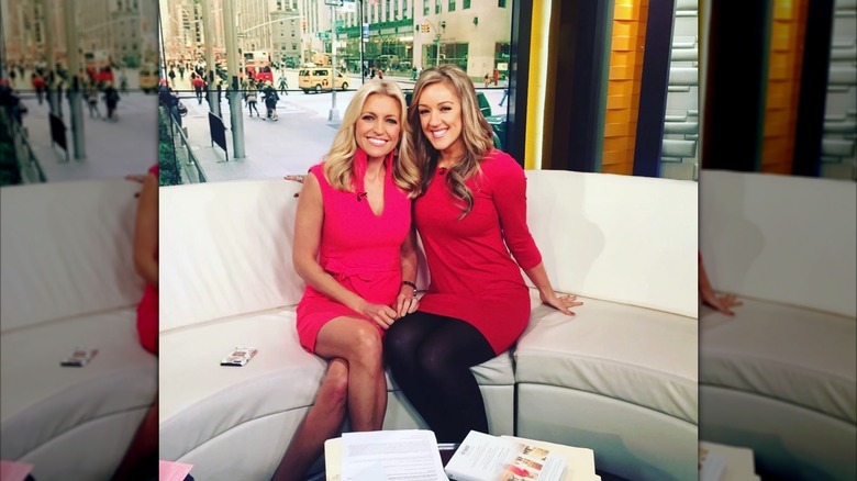 Ainsley Earhardt and Meghan Alexander seated and posing for a photo while on set.
