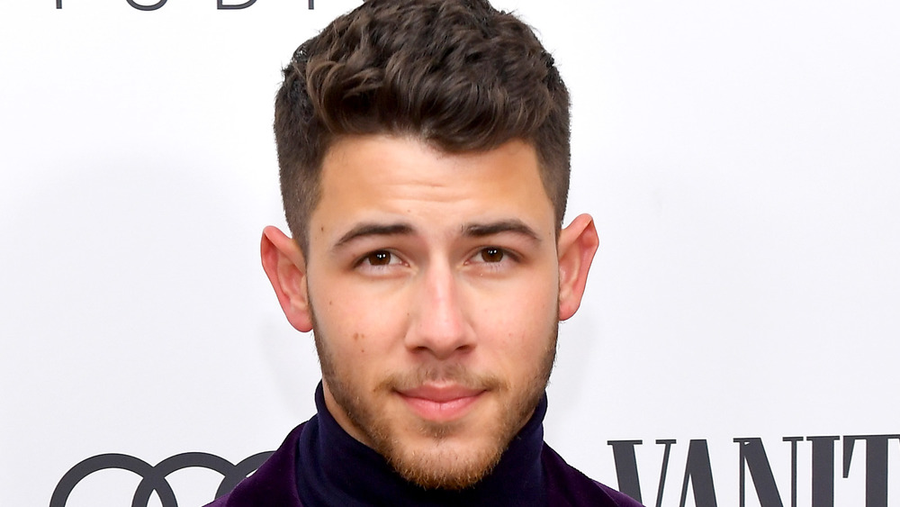 Nick Jonas posing for cameras smiling slightly 