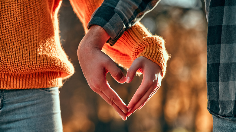 couple walking with hands joined in shape of a heart