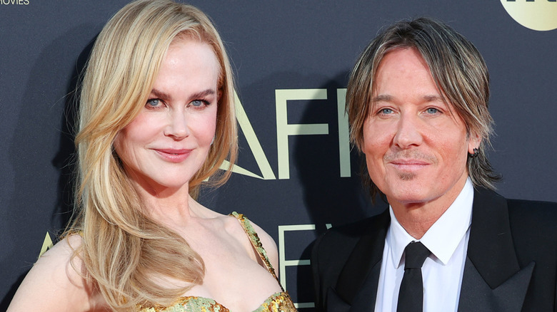 Nicole Kidman with a deep side part and Keith Urban with shaggy hair posing together on the red carpet