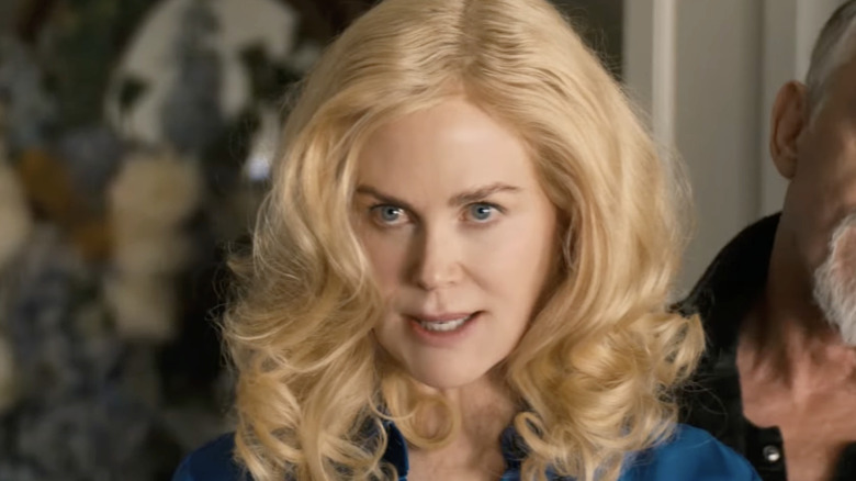 Nicole Kidman talking in a blond wig with large curls.
