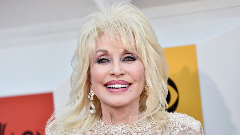 Dolly Parton smiling while attending an event in a sparkly white dress in 2016