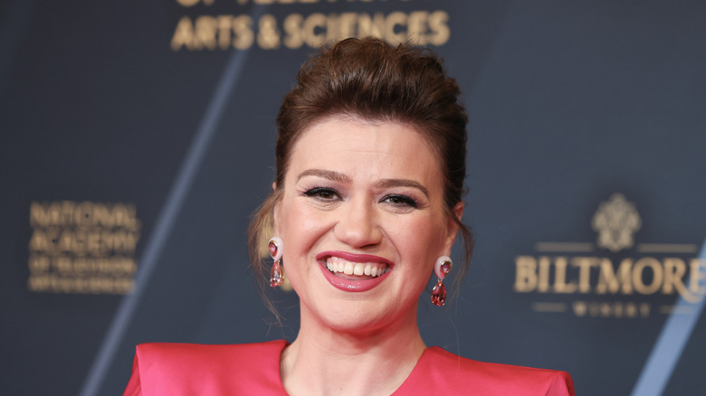 Kelly Clarkson smiling with teeth in a red outfit