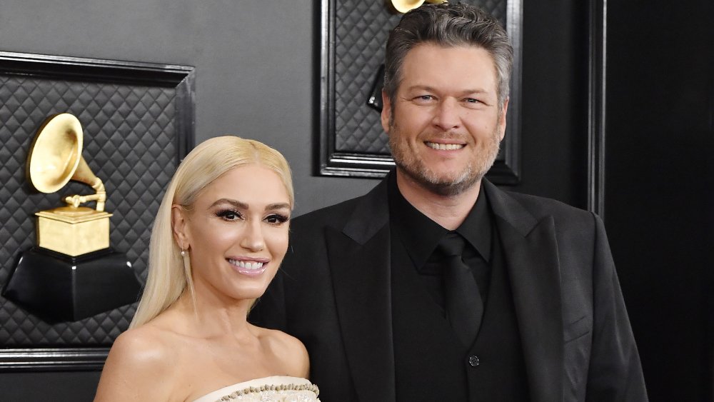 Gwen Stefani in a white dress, Blake Shelton in an all-black suit, both smiling at the Grammys