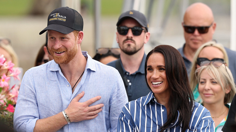 Prince Harry and Meghan Markle smiling in coordinating light blue shirts