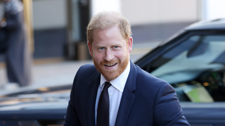 Prince Harry smiling with teeth in a navy suit