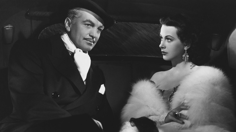 John Loder looks down pensively as Hedy Lamarr fixes her eyes on him.