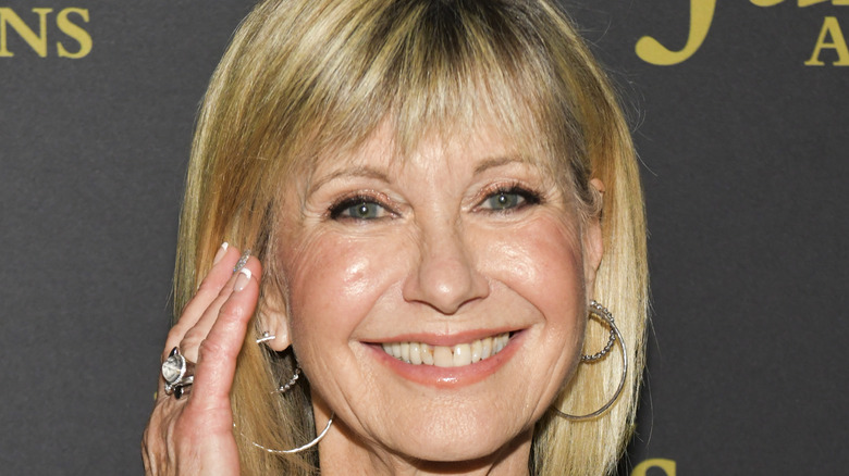 Olivia Newton-John smiles in gold hoop earrings