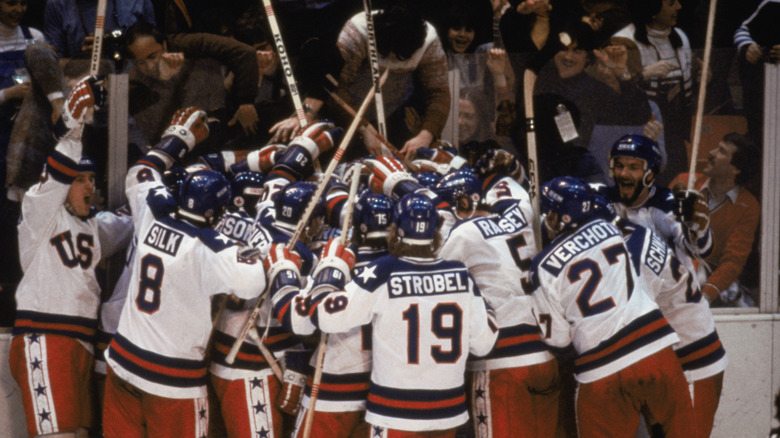 Mike Pavelich and Bob Suter with fellow hockey players, cheering