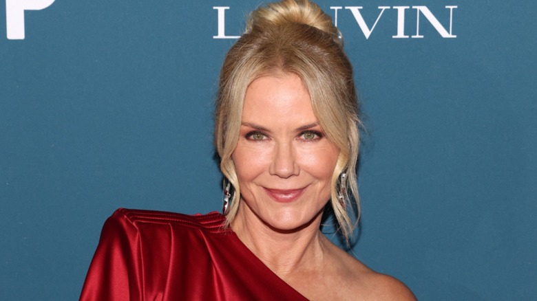 Katherine Kelly Lang, wearing full makeup and a red outfit, displays a soft smile