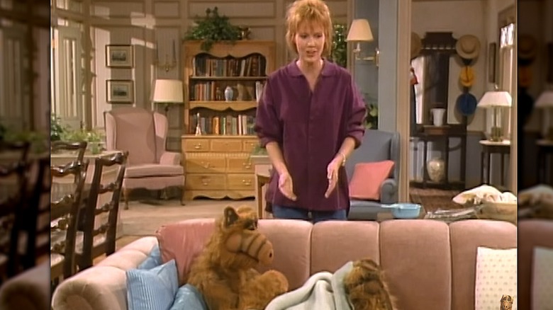 Anne Schedeen standing behind a couch
