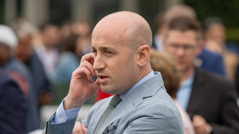 Stephen Miller looking concerned with his hand to his face in a grey suit