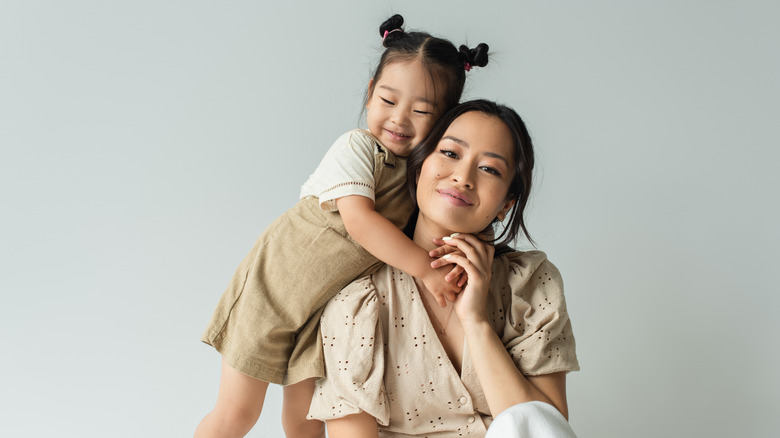 Smiling little girl with pig tails hugging her mom