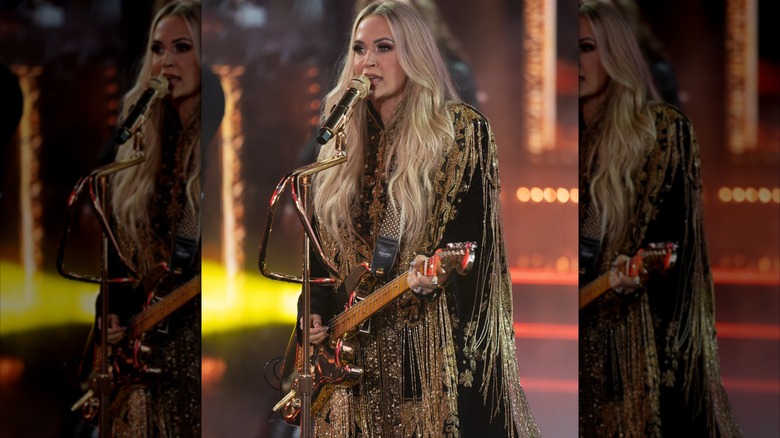 Carrie Underwood performs while wearing a rhinestone-and-fringe outfit.