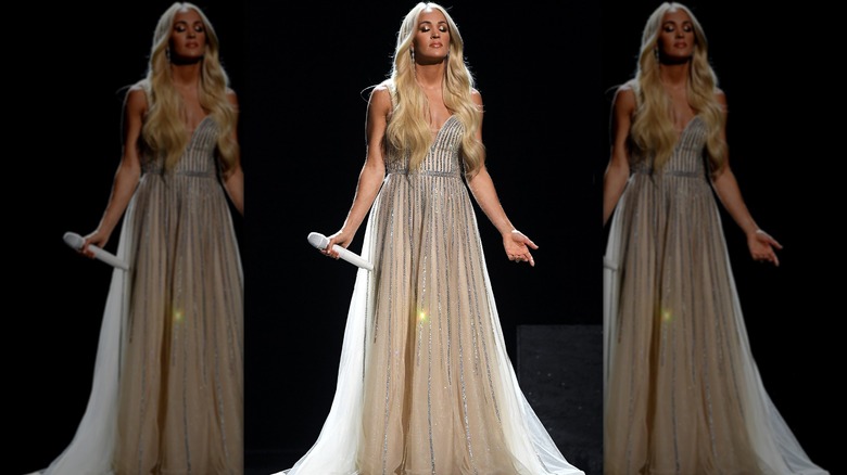 Carrie Underwood poses with her eyes closed and her hands stretched out while wearing an angelic dress.
