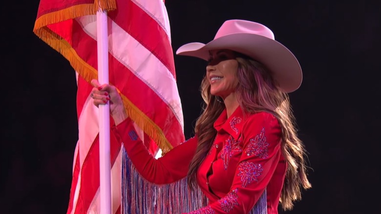 Kristi Noem holding the U.S. flag at the Wrangler National Finals Rodeo.
