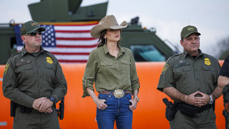 Kristi Noem posing with US Border Patrol agents in a cowgirl outfit.