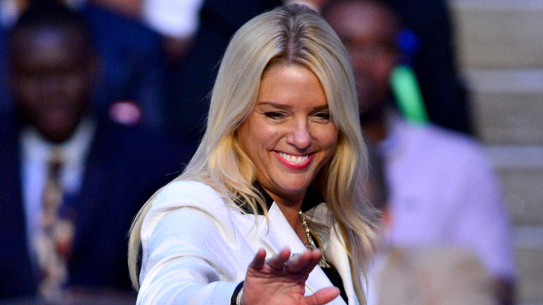 Pam Bondi smiles and waves at a political rally