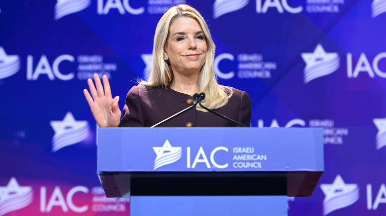 Pam Bondi gestures with her hand while speaking at a podium.