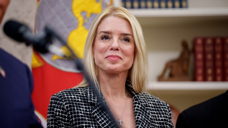 Pam Bondi smiling from behind a microphone
