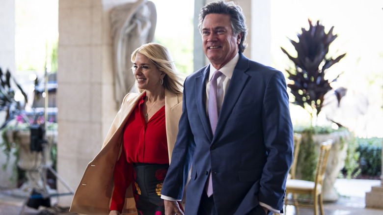 Pam Bondi and John Wakefield smiling as they walk into Mar-a-Lago.