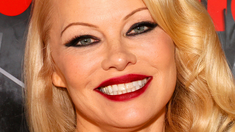 Pamela Anderson wears red lipstick and smiles