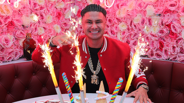 Pauly D smiling in front of a cake